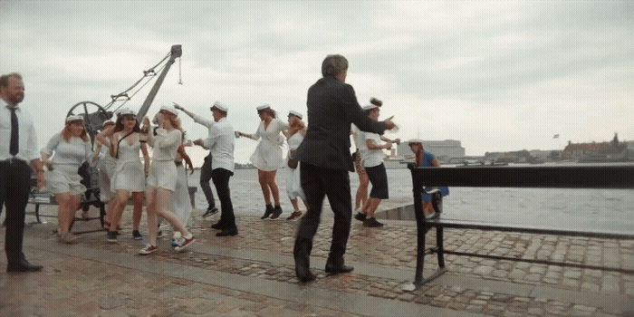 a group of people standing on a pier next to a body of water