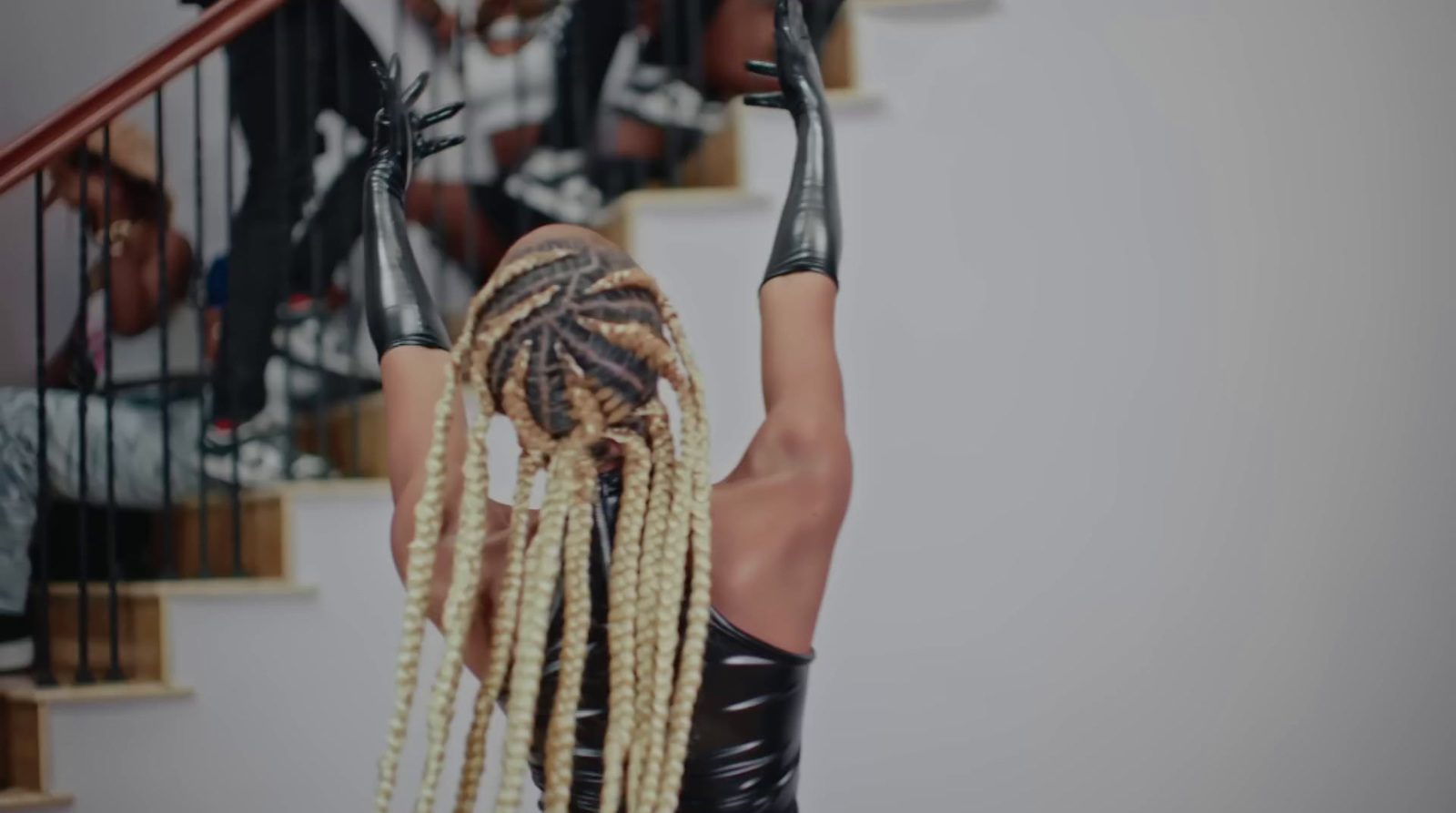 a woman with blonde dreadlocks standing in front of a stair case