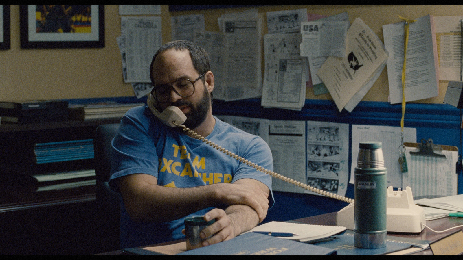 a man sitting at a desk talking on a phone