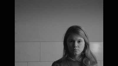 a woman standing in front of a white tiled wall