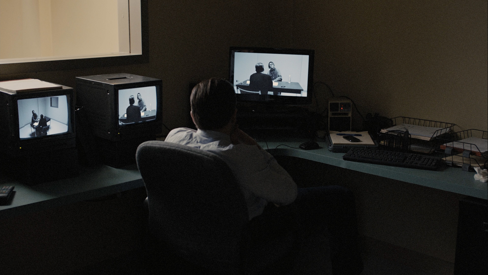 a person sitting in a chair in front of two televisions