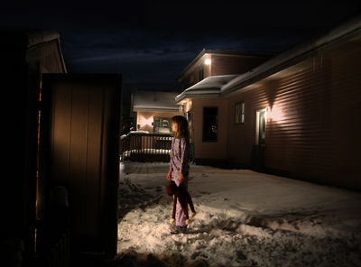 a woman standing in the snow in front of a house