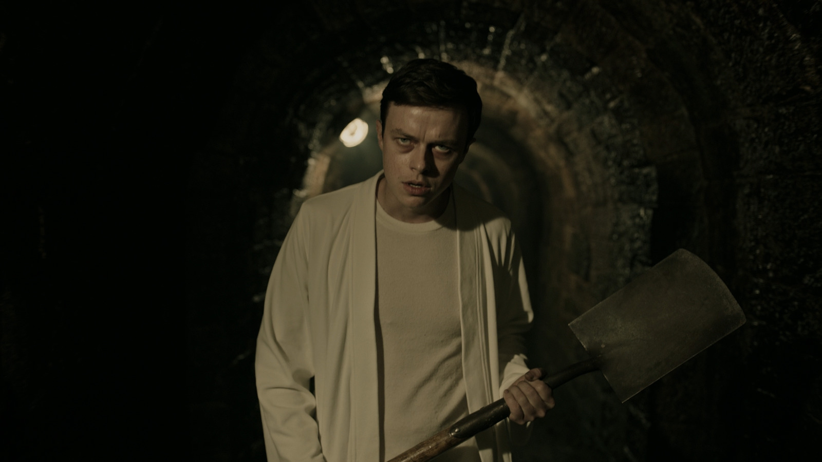 a man holding a large axe in a dark tunnel