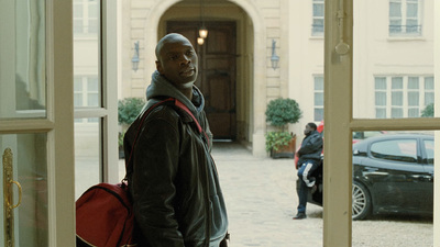 a man standing in front of a doorway with a red bag