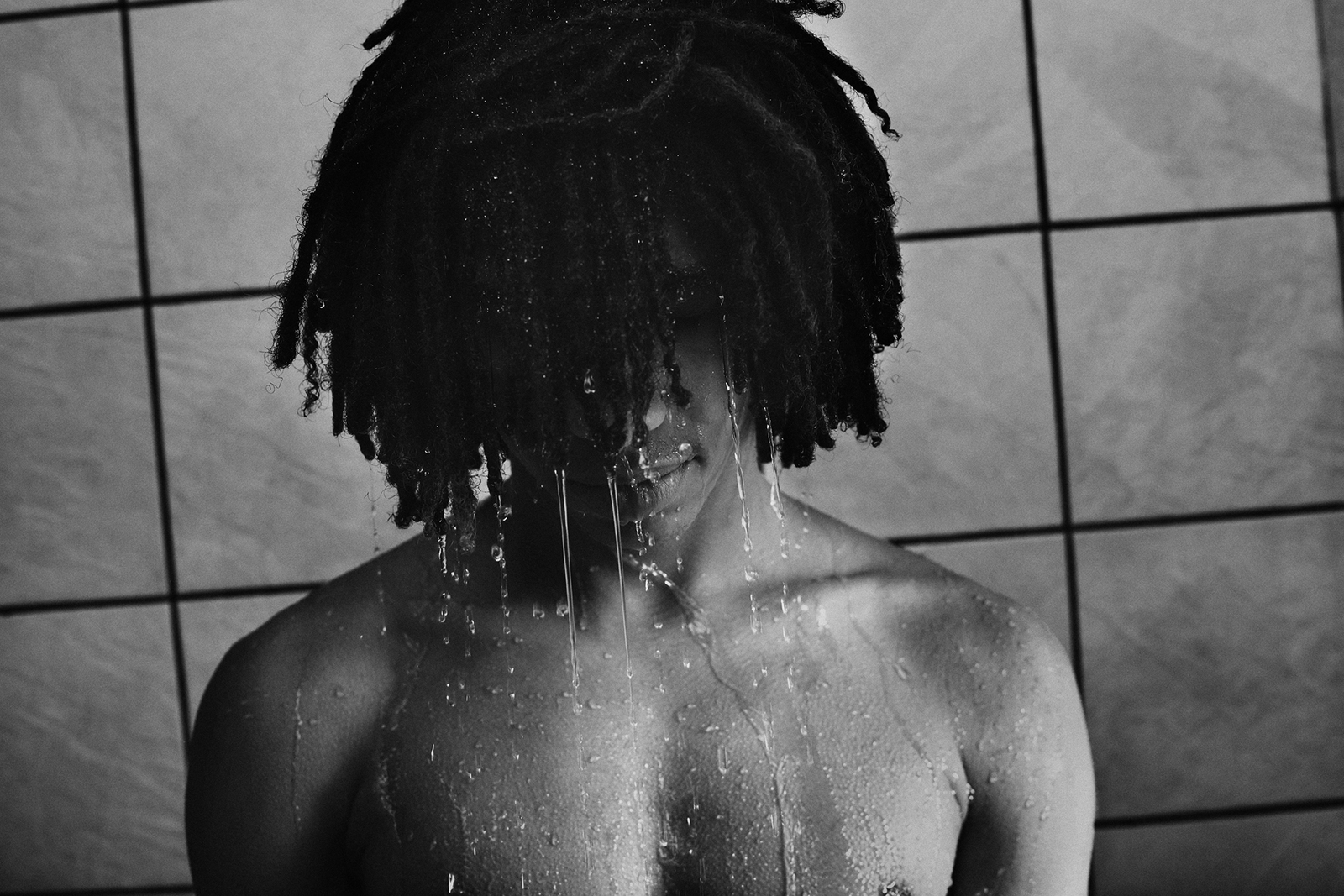 a man with dreadlocks standing in a shower