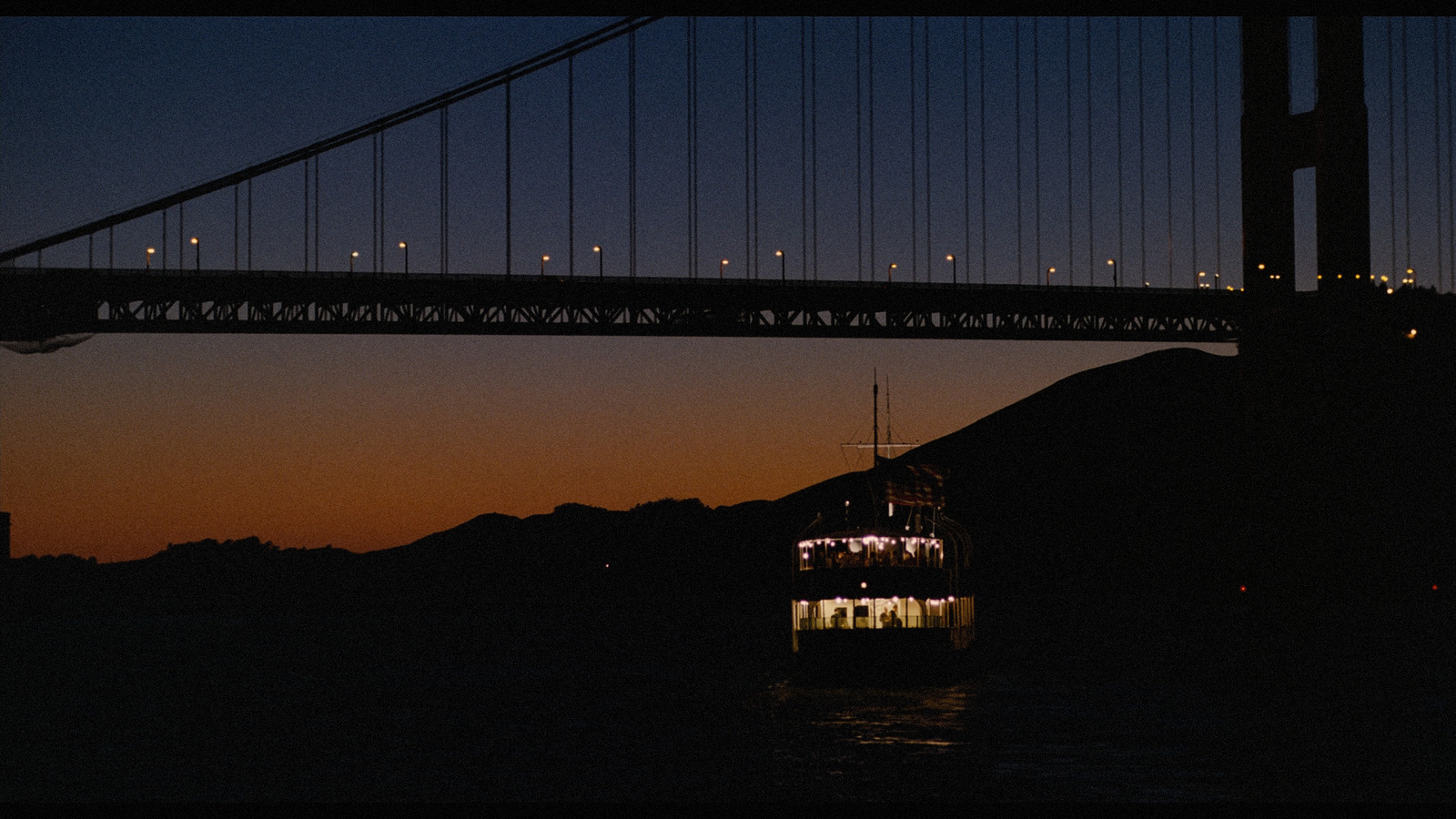 a large boat floating under a bridge at night