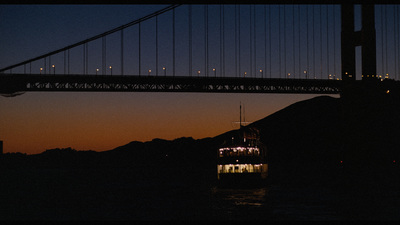 a large boat floating under a bridge at night