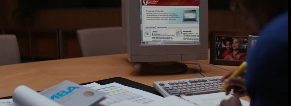 a person writing on a piece of paper in front of a computer