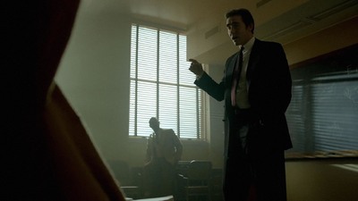 a man in a suit standing in front of a window