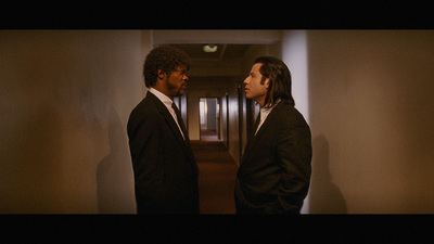 a couple of men standing next to each other in a hallway