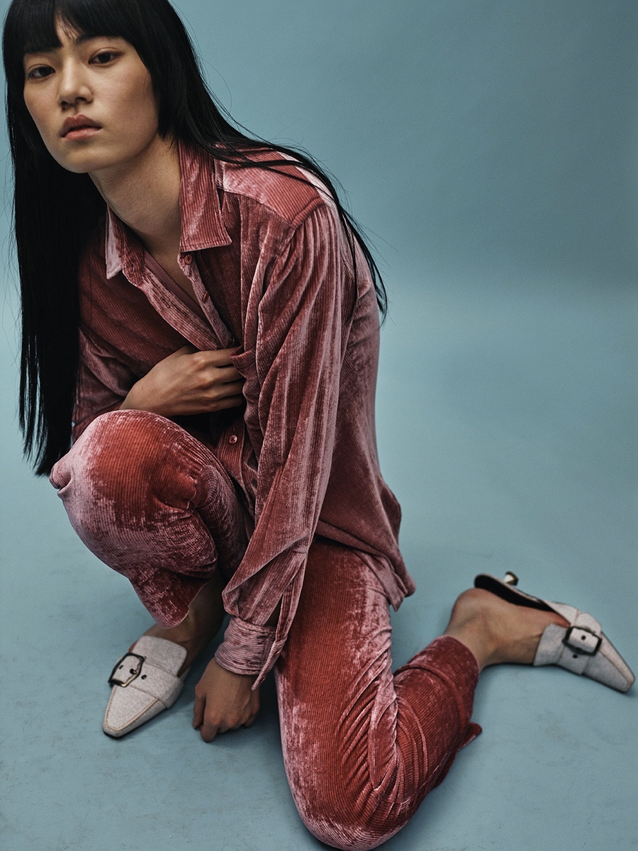 a woman sitting on the ground in a pink shirt and red pants