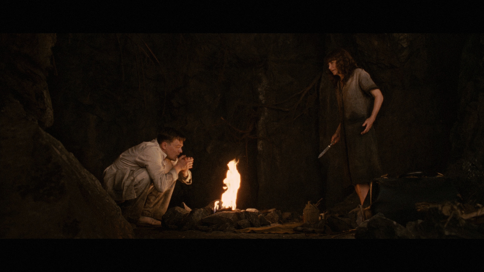 a man kneeling down next to a woman in a cave