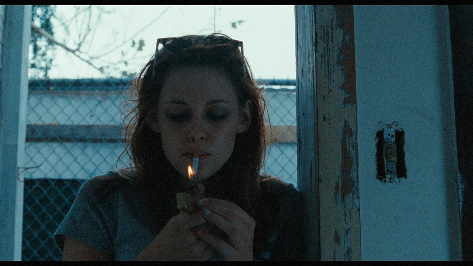 a woman smoking a cigarette in front of a chain link fence