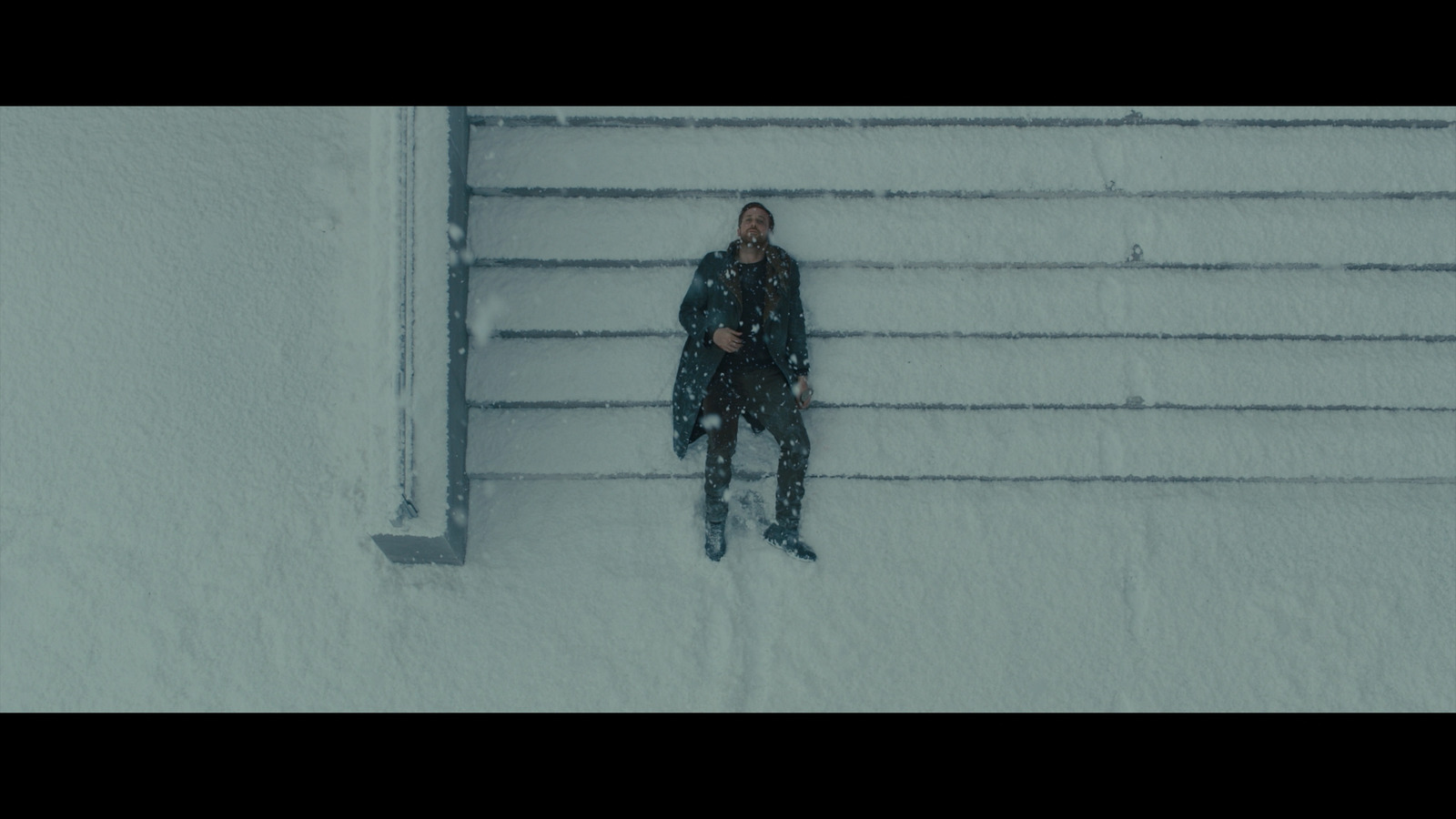 a person standing in the snow next to a fence