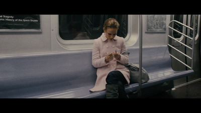 a woman sitting on a train looking at her phone