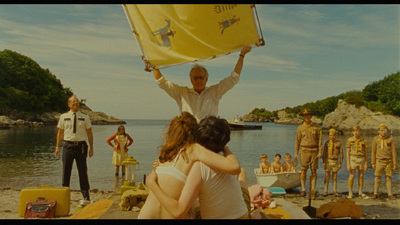 a group of people standing on top of a beach next to a body of water