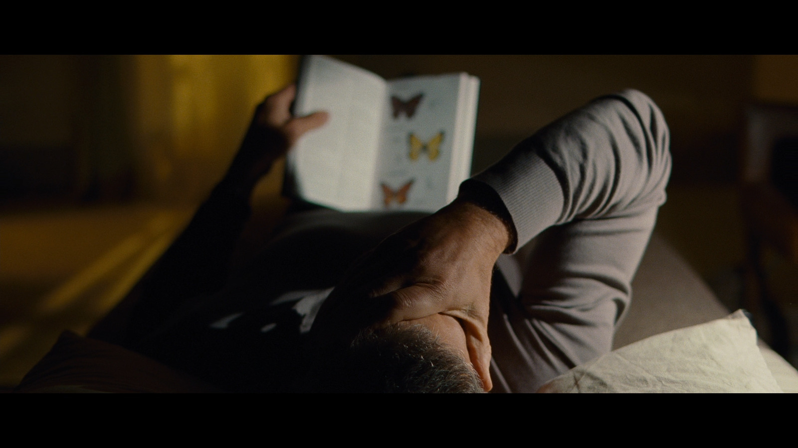 a man laying on a bed reading a book