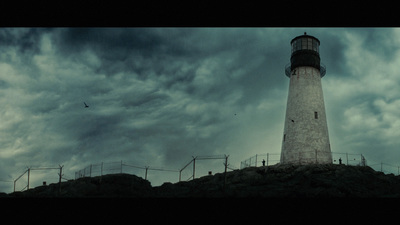 a lighthouse on top of a hill under a cloudy sky