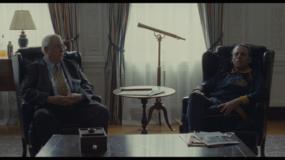 two men sitting in chairs in a living room