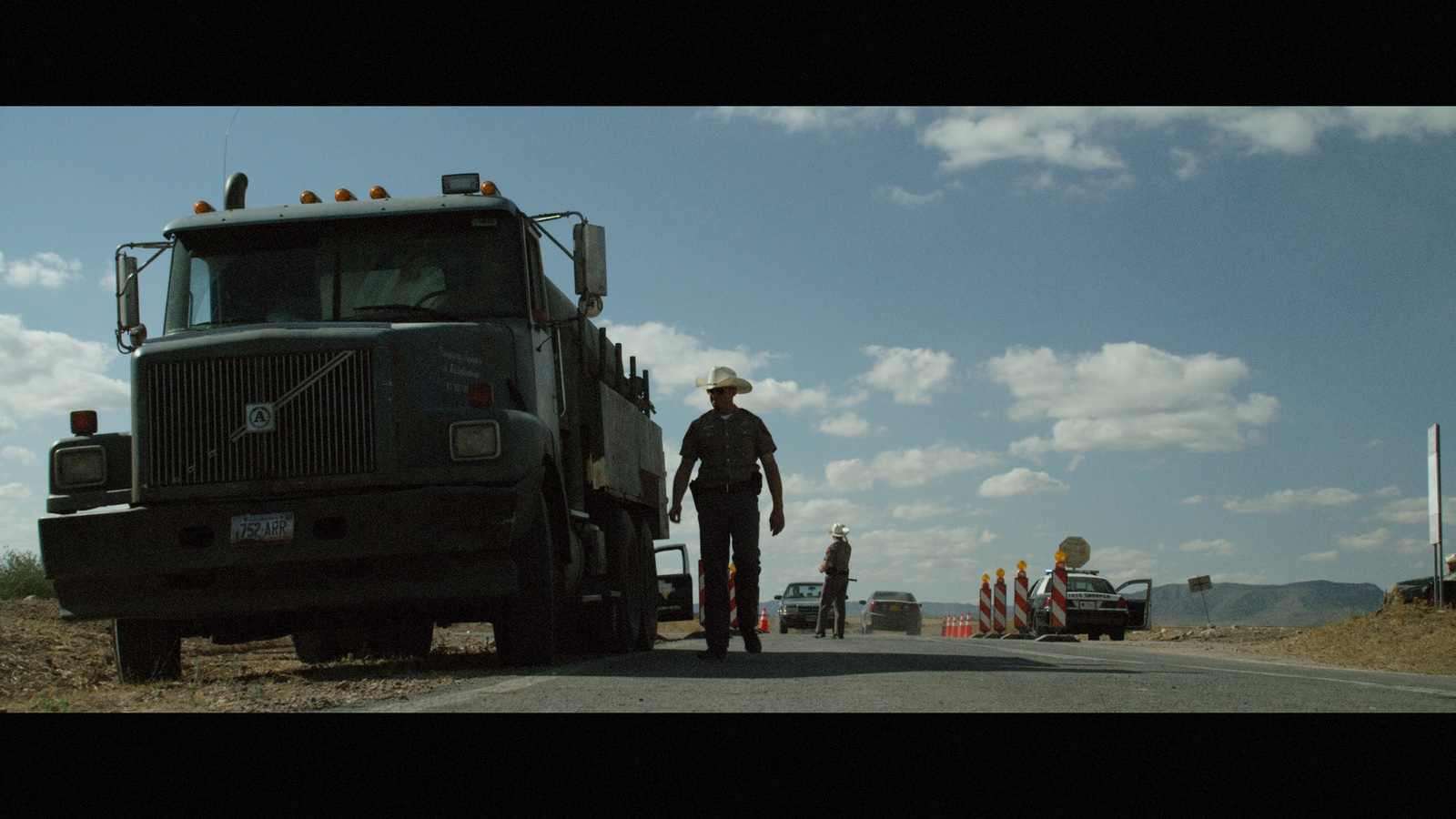 a man standing next to a large truck on the side of a road