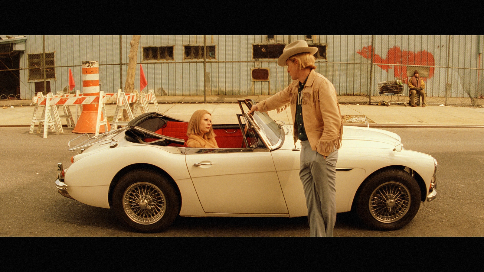 a man standing next to a woman in a white sports car