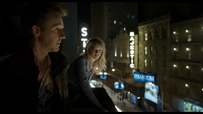 a man and a woman looking out of a window at night