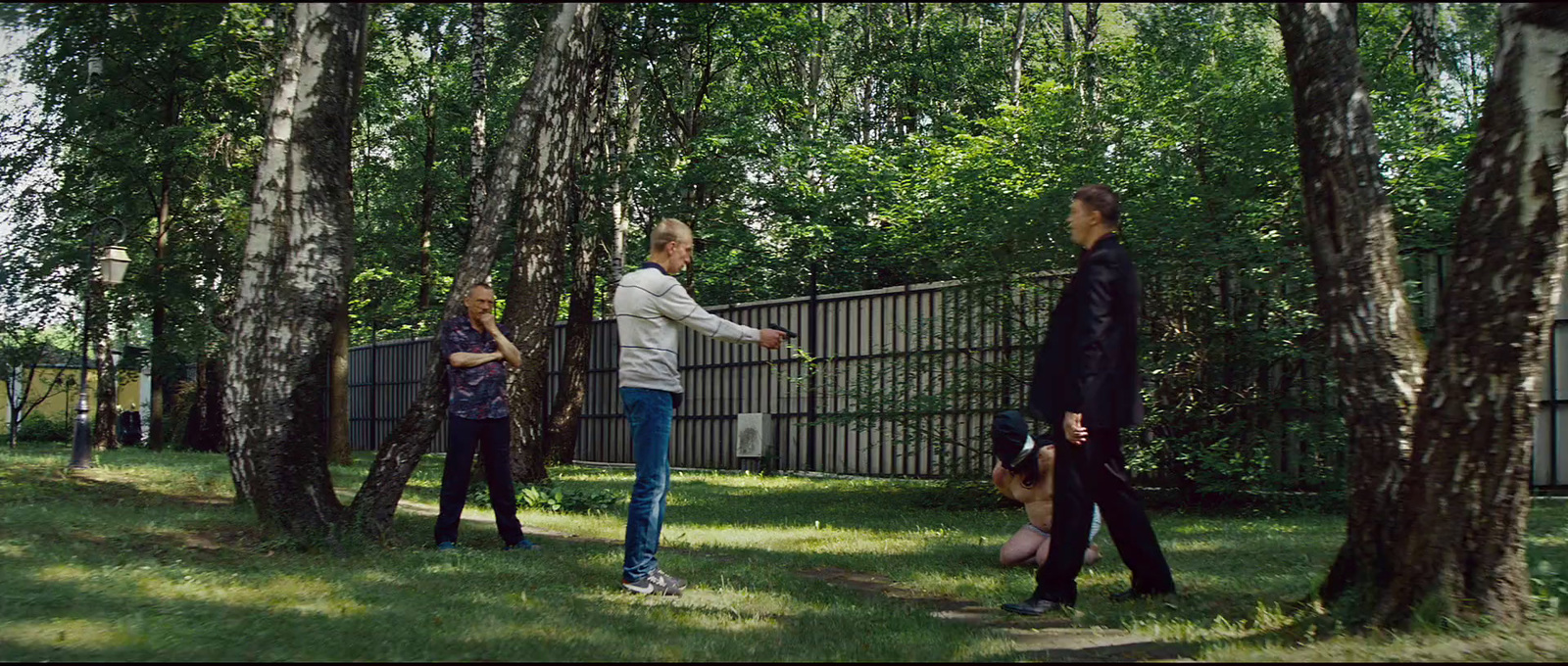 a group of people standing in the grass near trees