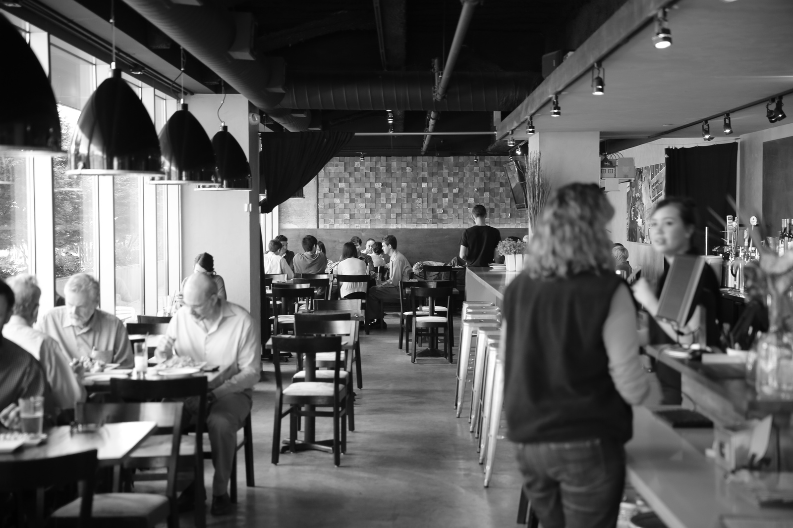 a black and white photo of people sitting at tables in a restaurant