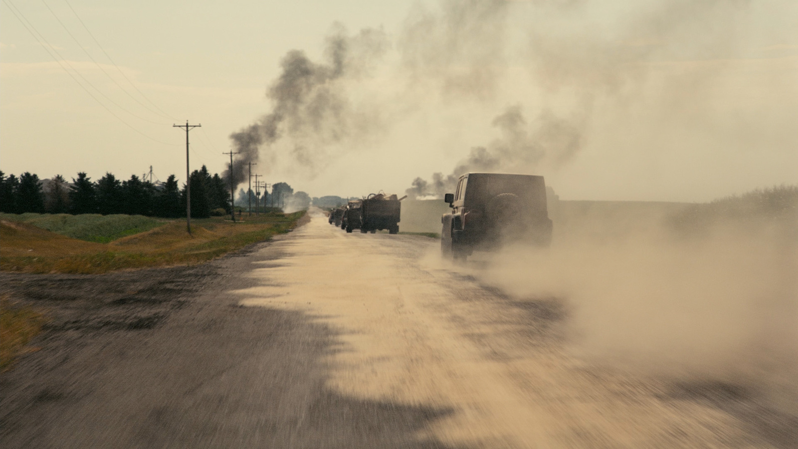 a group of trucks driving down a dirt road