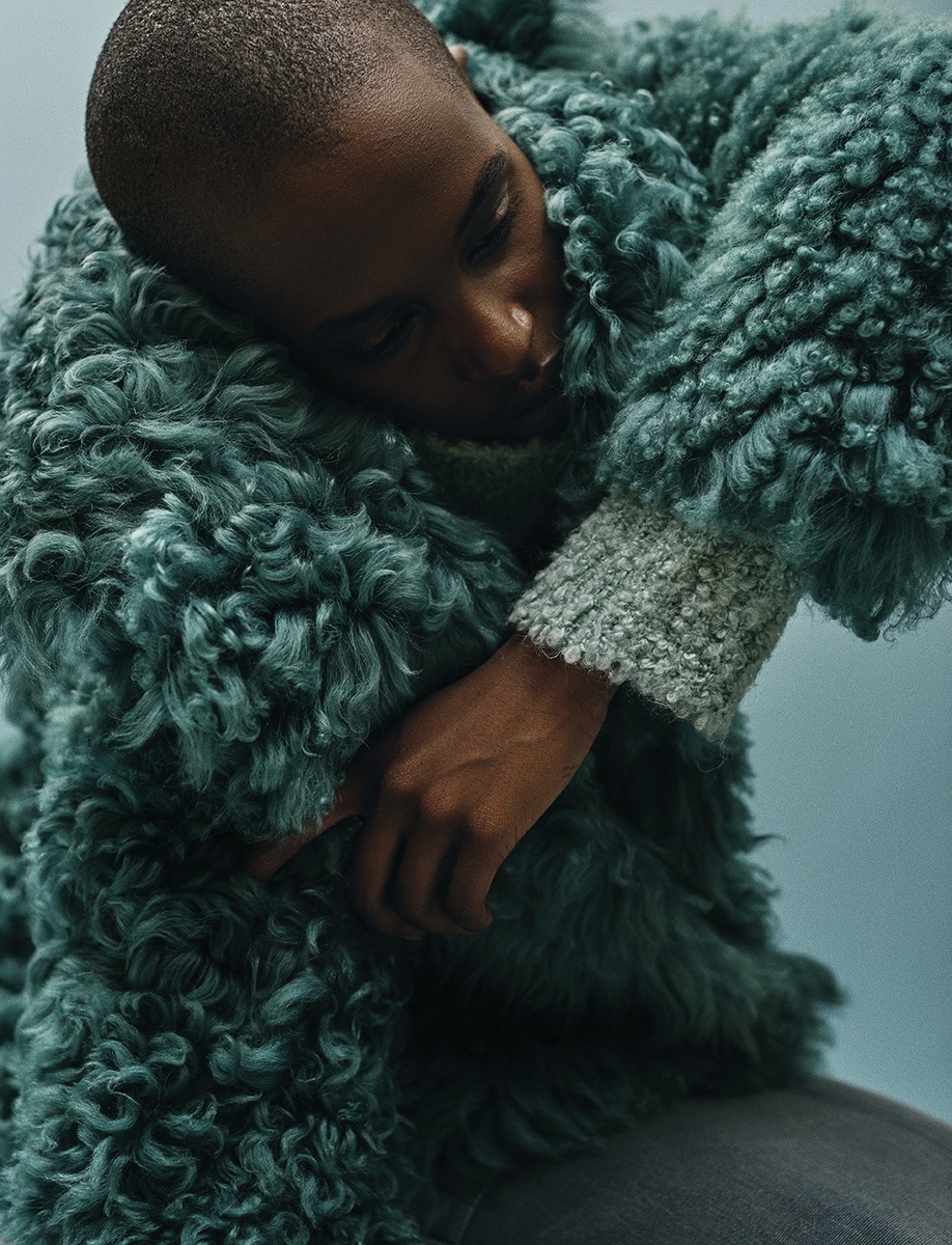 a man in a fuzzy green coat hugging a stuffed animal