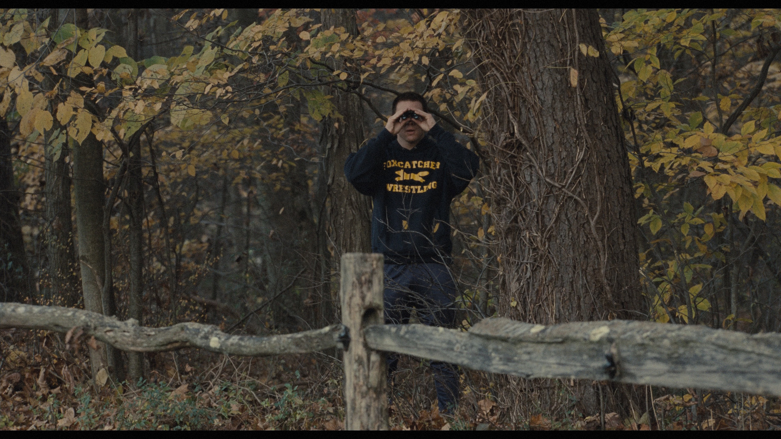 a man standing in front of a fence in the woods