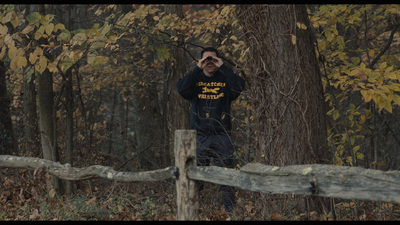 a man standing in front of a fence in the woods