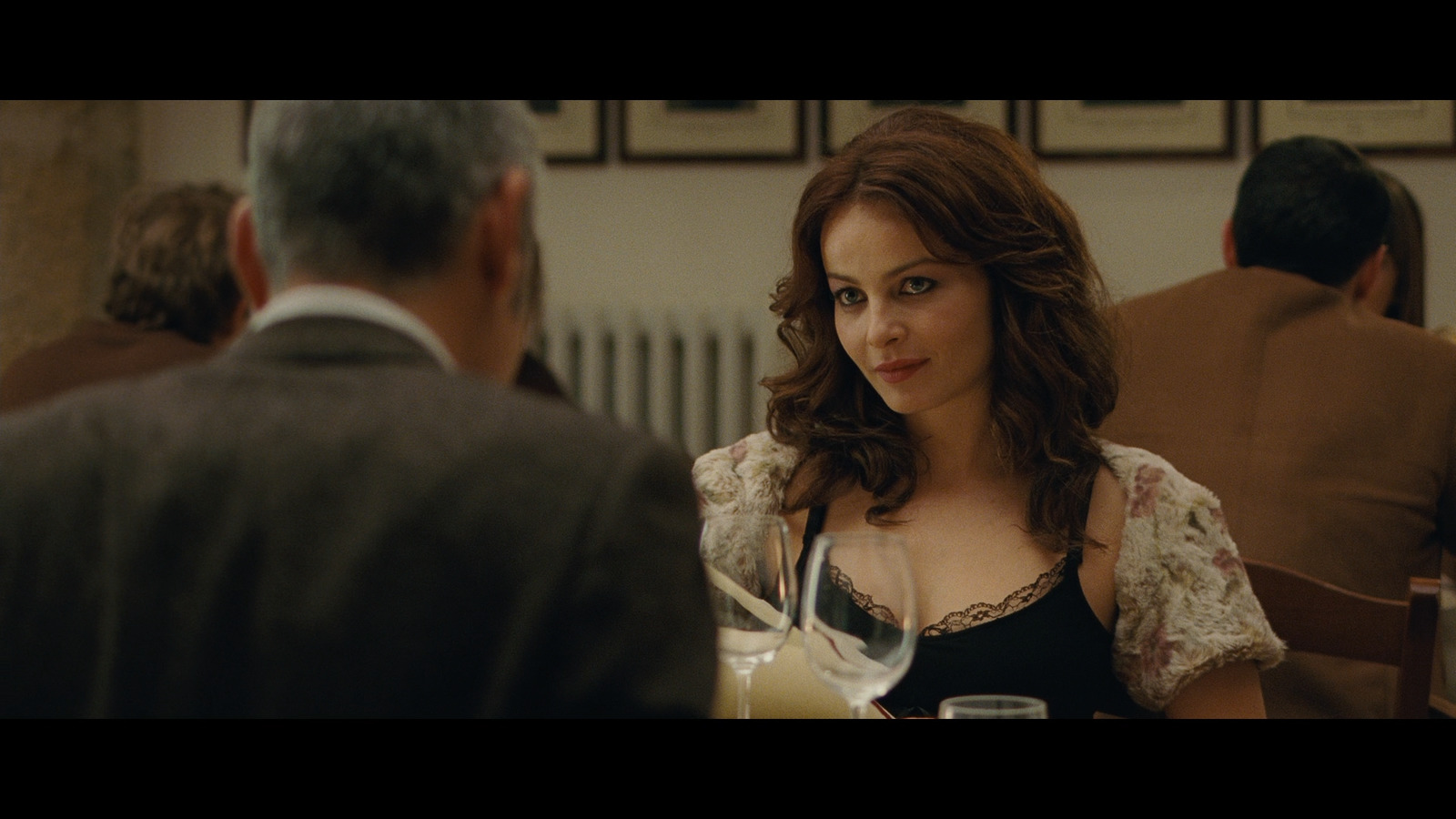 a woman sitting at a table with a glass of wine