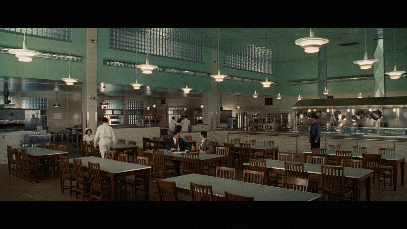 a group of people standing in a kitchen next to tables