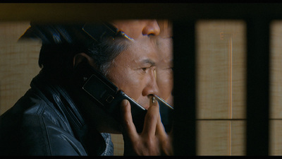 a man talking on a cell phone while holding a cigarette in his mouth