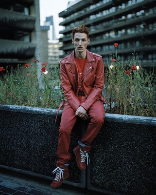 a man in a red leather jacket sitting on a wall