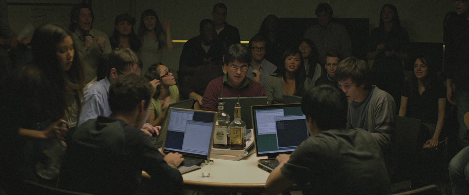 a group of people sitting around a table with laptops