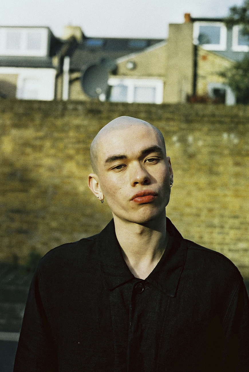 a man with a bald head standing in front of a brick wall