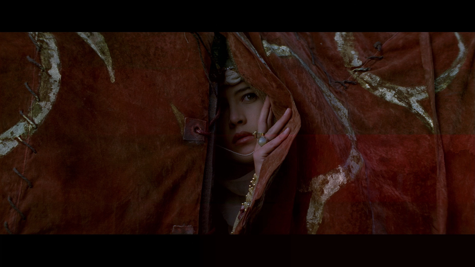 a woman hiding behind a red cloth with her hand on her face