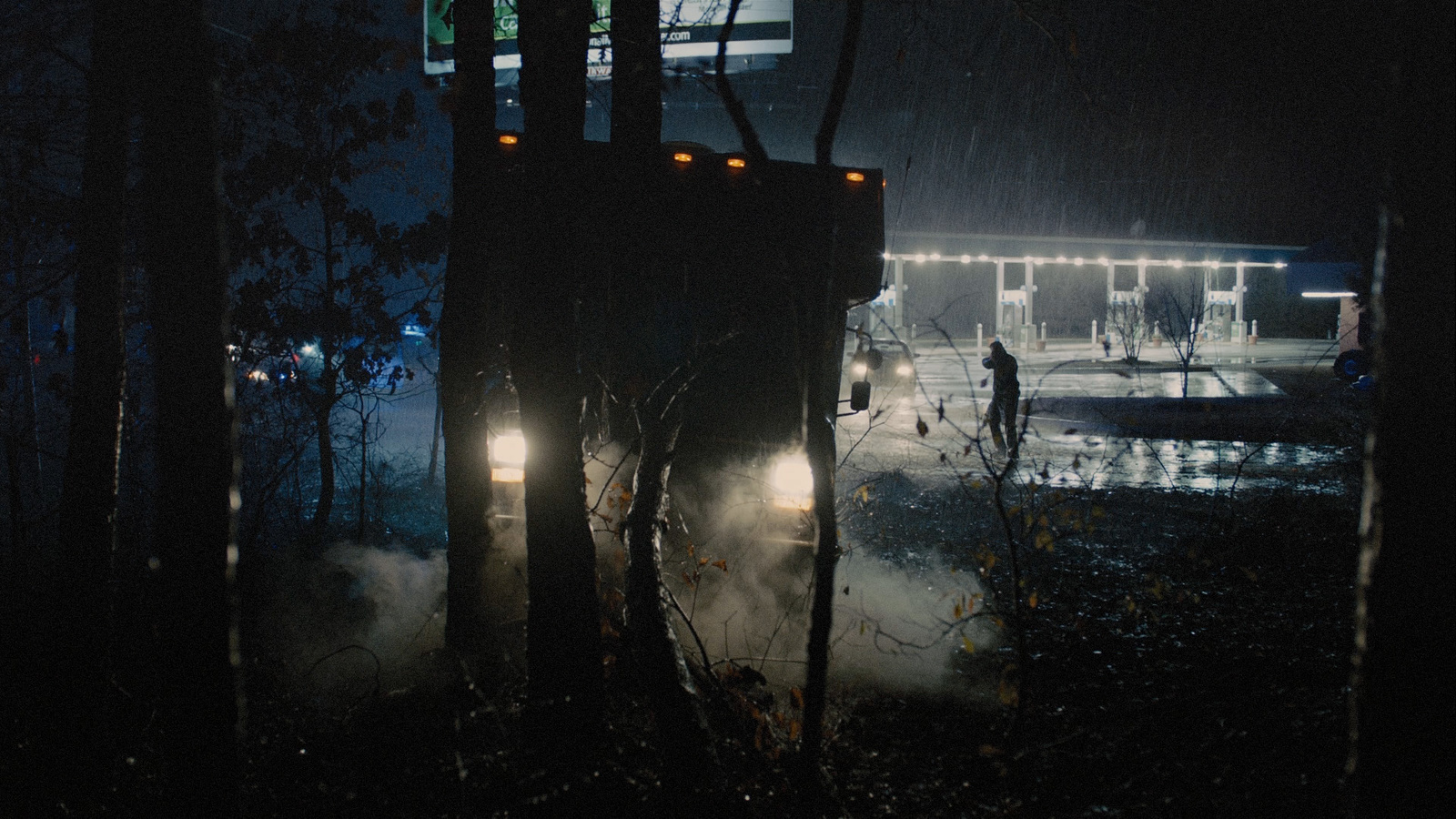 a truck driving through a forest at night