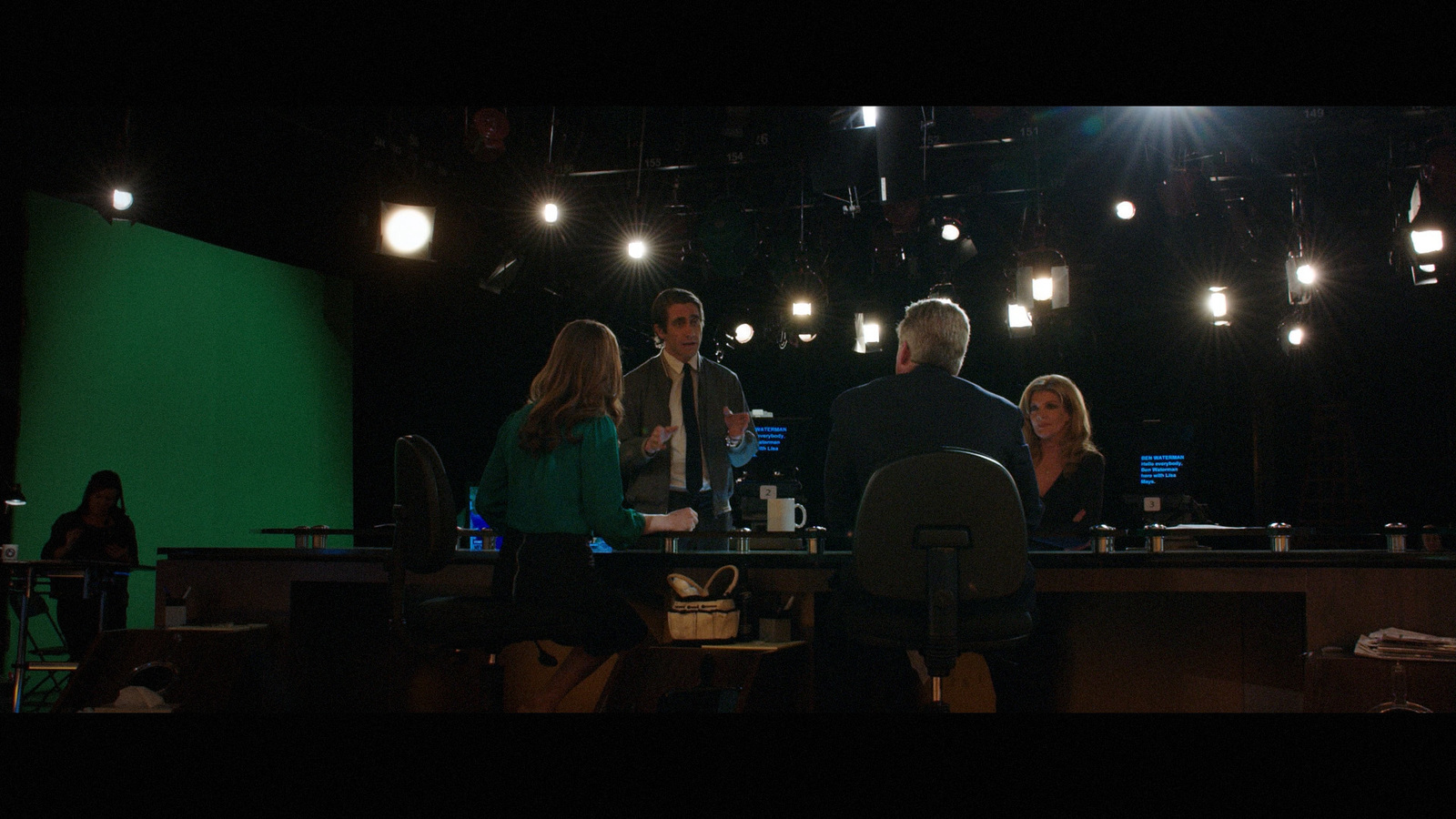 a group of people sitting at a table in front of a green screen