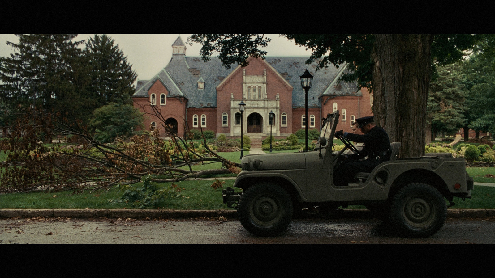 a man driving a jeep down a street next to a tree