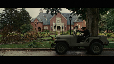 a man driving a jeep down a street next to a tree