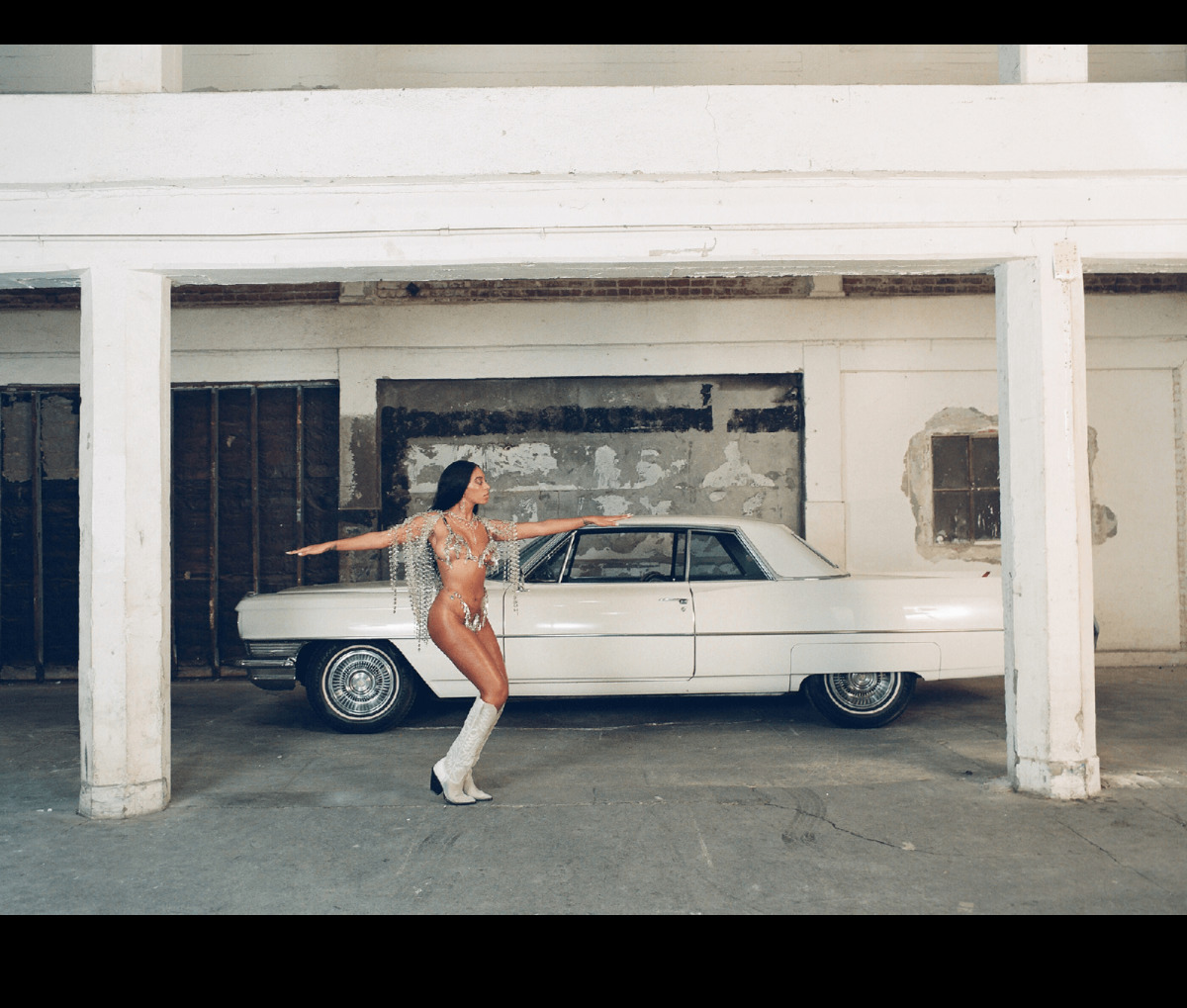 a woman standing next to a white car in a garage