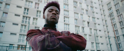 a man with a mohawk standing in front of a tall building