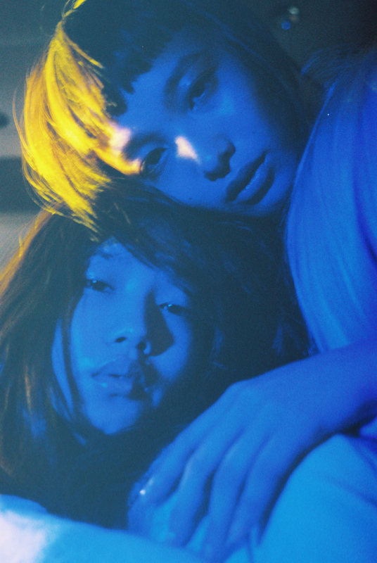 two young women laying in bed with their arms around each other