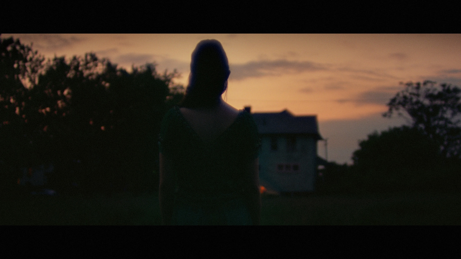 a woman standing in front of a house at sunset