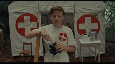 a young man holding a camera in front of a tent