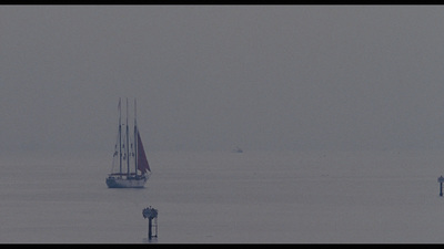 a sailboat in the middle of the ocean on a foggy day