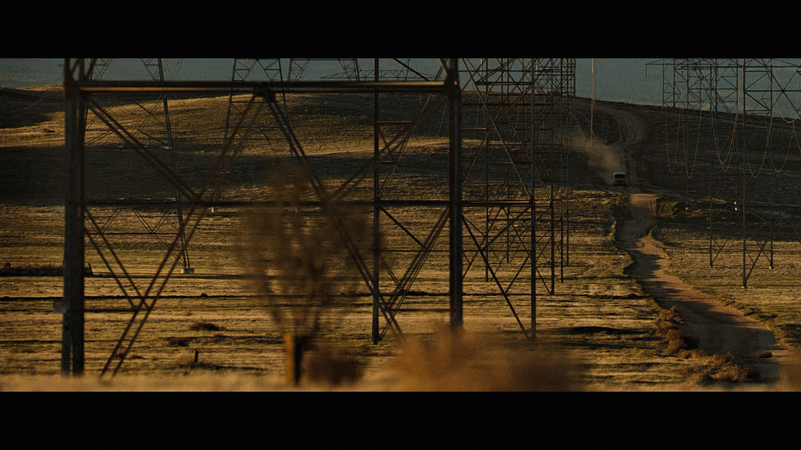 a man walking down a dirt road next to power lines